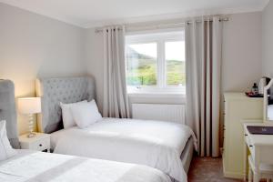 a bedroom with two beds and a window at Grimisdale Guest House in Leverburgh
