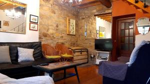 ein Wohnzimmer mit einem Sofa und einem TV in der Unterkunft Casa de Piñeiro y SPA (opcional) in Santiago de Compostela