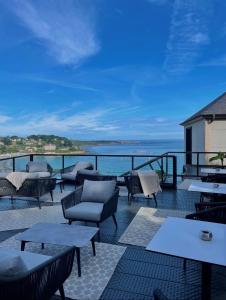 a patio with tables and chairs and the ocean at L'Agapa Hôtel - Spa Codage in Perros-Guirec