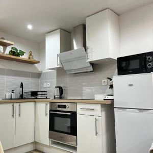 una cocina con electrodomésticos blancos y armarios blancos en Beau petit appartement au coeur de l'ariege. en Tarascon-sur-Ariège