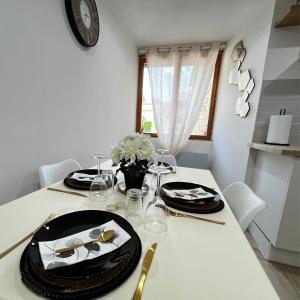 mesa de comedor con platos y vasos y reloj en Beau petit appartement au coeur de l'ariege. en Tarascon-sur-Ariège