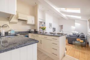 a kitchen with white cabinets and a living room at Windsor Gem: 1-Bed Oasis Near Castle in Windsor