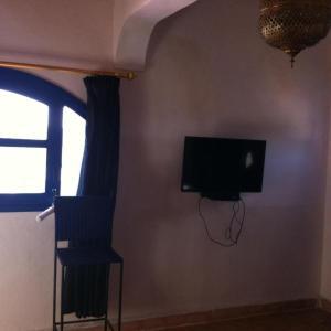 Habitación con TV, silla y ventana. en Room in Guest room - Room in villa Lair De La Mer no0969, en Sidi Kaouki