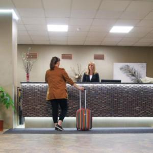 a woman walking with a suitcase in an airport at Hotel Belaria Resort in Opava