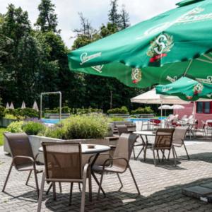 a group of tables and chairs with green umbrellas at Hotel Belaria Resort in Opava