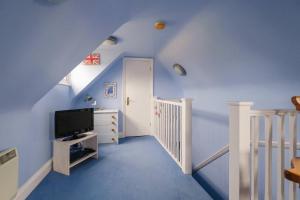 Habitación con paredes azules y escalera con TV. en 2 Ogilvie Lodge, en Thorpeness