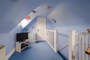 a room with blue walls and a staircase with a tv at 2 Ogilvie Lodge in Thorpeness