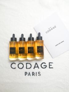 a set of three bottles of orange paint next to a envelope at L'Agapa Hôtel - Spa Codage in Perros-Guirec