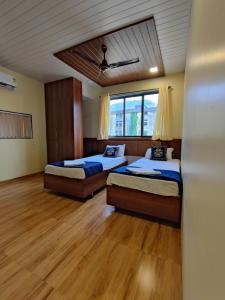 two beds in a room with wooden floors at Hotel Starlit in Navi Mumbai