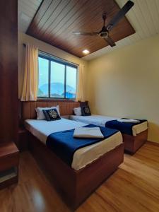 a bedroom with two beds and a ceiling fan at Hotel Starlit in Navi Mumbai