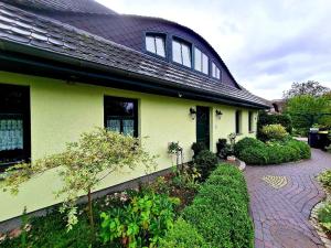 a yellow house with a black roof and a walkway at Hus Sünnschien in Alt Reddevitz