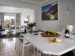 een witte keuken met een tafel met fruit en wijnflessen bij Seaview Camps Bay 6 Sleeper in Kaapstad