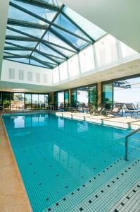 ein großer Pool mit Stühlen in einem Gebäude in der Unterkunft L'Agapa Hôtel - Spa Codage in Perros-Guirec