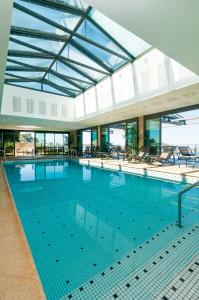 - une grande piscine avec des chaises dans un bâtiment dans l'établissement L'Agapa Hôtel - Spa Codage, à Perros-Guirec