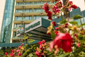 a sign in front of a building with red flowers at Hotel Slavyanski in Sunny Beach