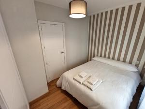 Un pequeño dormitorio con una cama blanca con dos libros. en Apartamento DON MANUEL, en Córdoba
