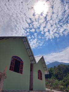 a small house with a cloudy sky in the background at Mini lar 2 in Caparaó Velho +4 photos