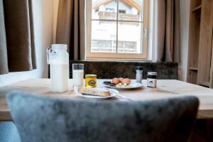 ナウダースにあるROSENHOF- Premium & Landhaus Apartments & Wellness & Erlebnisbauernhofの卵、パン、ミルク1本付きのテーブル