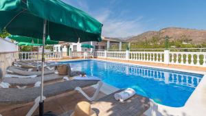 una piscina con sedie a sdraio e ombrellone di Villa Cañadu Nerja by Ruralidays a Nerja