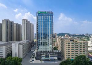Holiday Inn Express Shantou Chenghai في شانتو: مبنى زجاجي طويل في مدينة بها مباني