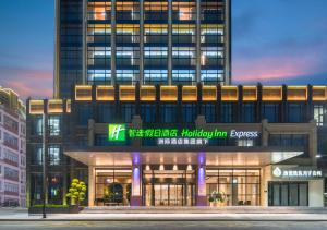 een hoog gebouw met een bord ervoor bij Holiday Inn Express Shantou Chenghai in Shantou