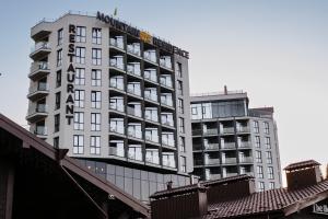 a tall white hotel building next to another building at Mountain Residence Apartments & Chalet in Bukovel