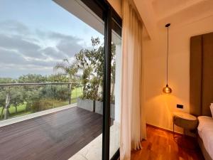 een slaapkamer met een balkon met uitzicht op de tuin bij Golf view Villa with Jacuzzi- By AppartAli in Bouskoura