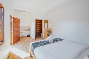 a white bedroom with a bed and a bathroom at Pondok Kita in Canggu