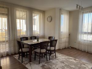 a dining room with a table and chairs and windows at Panorama view apartment in Sandanski