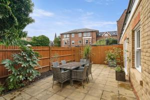 a patio with a table and chairs and a fence at Molesey Apartments in East Molesey