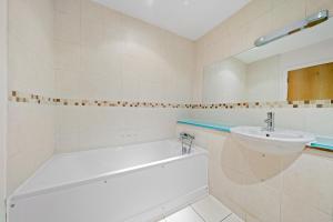 a white bathroom with a sink and a bath tub at Molesey Apartments in East Molesey