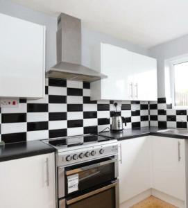 a kitchen with a black and white checkered wall at The Dunstable House in Houghton Regis