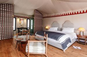 a bedroom with a bed and a table and chairs at Merzouga luxury desert camps in Merzouga