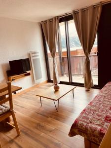 a room with a bed and a table and a window at Magnifique studio 4 pers avec balcon vue montagne in Orcières