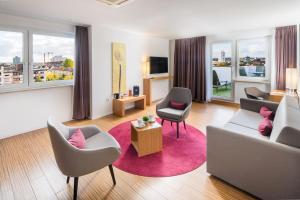 a living room with a couch and chairs and windows at Hotel Newton Heilbronn in Heilbronn