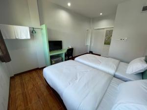 a hotel room with two beds and a desk at Chiang Kham Ruk Khun Hotel in Chiang Kham
