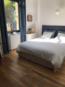 ein Schlafzimmer mit einem Bett und einem großen Fenster in der Unterkunft LE JARDIN D'ALEXANDRE in Orléans