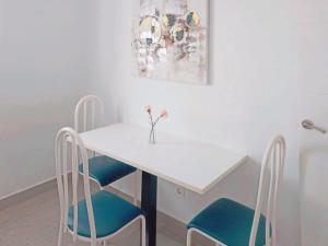 a white table with two chairs and a vase with flowers at Live La Laguna Gracia in Las Lagunas