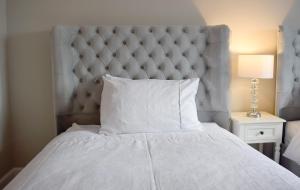 a bedroom with a white bed with a large headboard at Grimisdale Guest House in Leverburgh