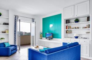 sala de estar con sofá azul y TV en Le Capannelle, en SantʼAgata sui Due Golfi