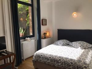 um quarto com uma cama e uma janela em LE JARDIN D'ALEXANDRE em Orléans
