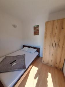 1 dormitorio con 1 cama y armario de madera en Apartments HN, en Igalo