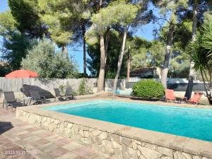 una piscina en un patio con sillas y sombrilla en Casa Mas Montanas vakantiehuis met zwembad Max 10 pers Vlakbij Valencia en Godelleta