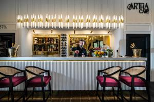 a bar with four chairs and a man behind the counter at ZET Hotel in Timişoara