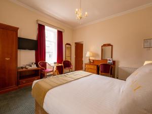 a hotel room with a bed and a desk at Grant Arms Hotel in Grantown on Spey