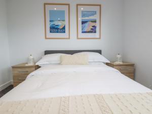 um quarto com uma grande cama branca com três fotografias na parede em Beagle Cottage em Saint Dennis