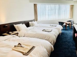 ein Hotelzimmer mit 3 Betten und Handtüchern darauf in der Unterkunft Awa Kanko Hotel in Tokushima