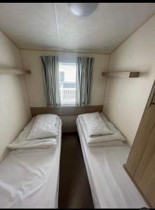 a small room with two beds and a window at Lyon’s Robin Hood Rhyl caravan sbw in Rhyl