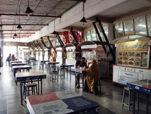 two people sitting at tables in a restaurant at Hotel Syariah Selamat Sukabumi in Sukabumi