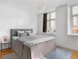 um quarto branco com uma cama grande e 2 janelas em Sanders Leaves - Charming Three-Bedroom Apartment In Downtown Copenhagen em Copenhague